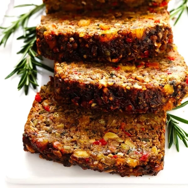 Slices of Pureganic Cafe's healthy meatloaf, garnished with fresh rosemary on a white plate.