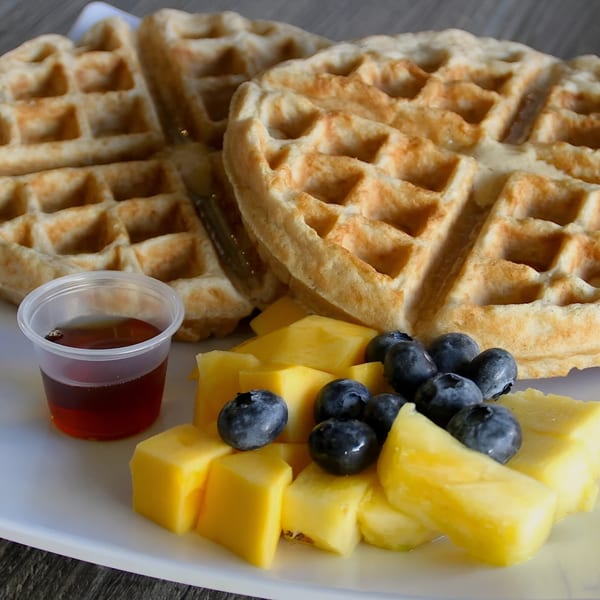 Golden waffles with fresh blueberries, pineapple, mango, and a side of maple syrup.