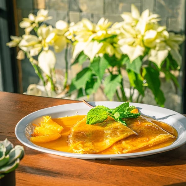 Pureganic Cafe's healthy crepes with orange slices and mint on a wooden table.
